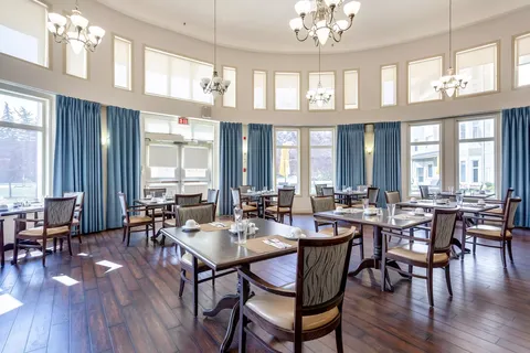 Dining room with set tables, blue curtains and high windows