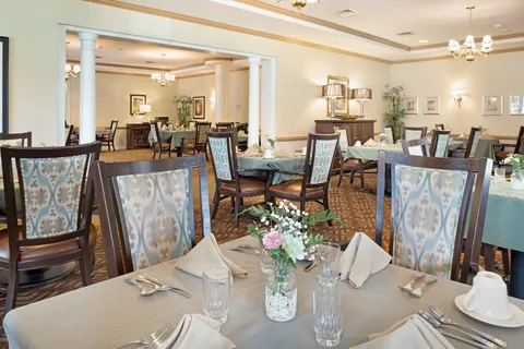 Dining room with set tables, blue patterned chairs and white columns.
