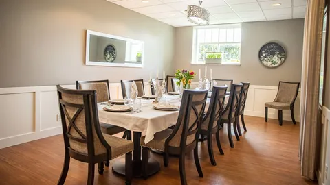 Dining room with a long table, upholstered chairs, candles and flowers
