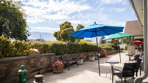 Patio with metal seating, blue and green umbrellas, and flower planters