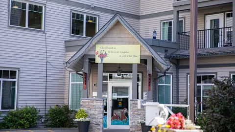 Covered residence entrance with stone pillars, flower planters and glass doors