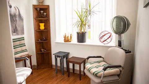 Salon corner with a chair, hooded hair dryer, shelving and window