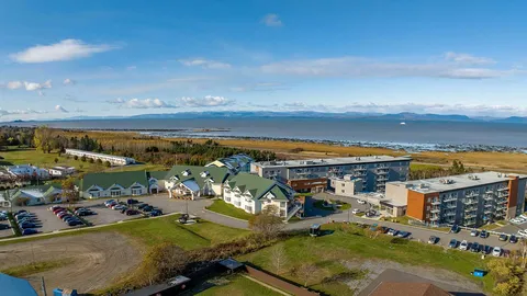 Aerial view of connected residences, parking areas and grounds beside the river