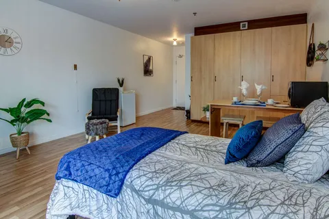 Bedroom with blue bedding and wooden cupboards.