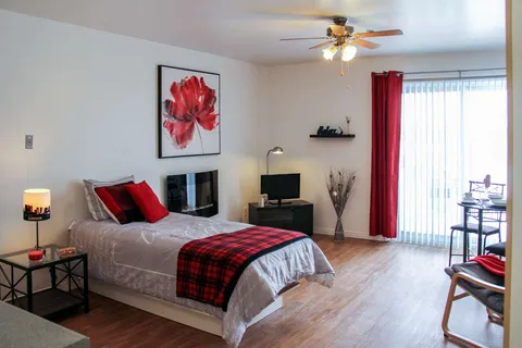 Studio bedroom with red bedding and a patio door.