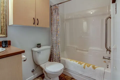 Bathroom with a bathtub, toilet and wooden cupboards.