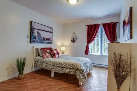 Bedroom with a bed and red curtains beside a window.
