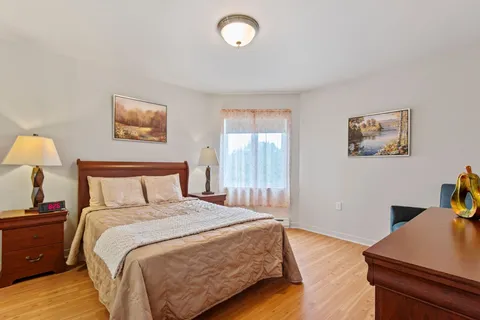 Bedroom with a bed, dresser, armchair and large window