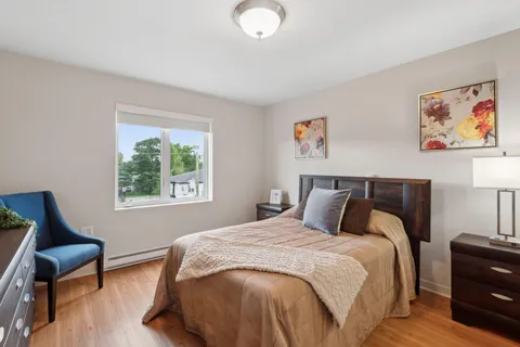 Bedroom with a bed, chest of drawers, blue armchair and a window