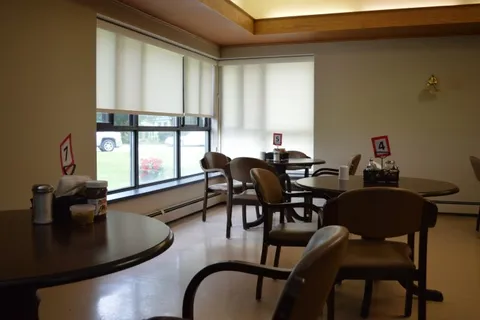 Dining tables beside large windows with roller blinds