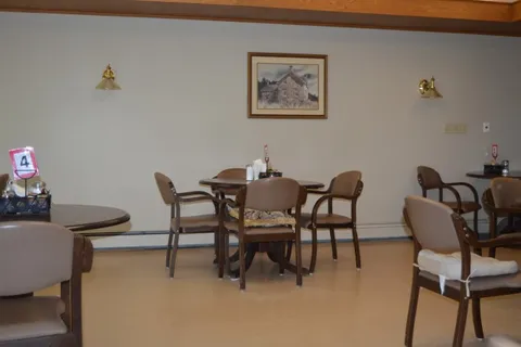 Round dining tables and upholstered chairs beneath a framed landscape