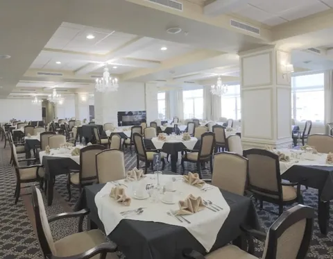 Dining room with round tables, upholstered chairs and chandeliers