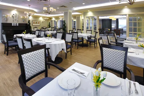 Dining room with set round tables and upholstered chairs.