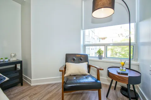 Suite sitting corner with an armchair, table and window.