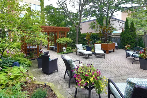 Courtyard patio with armchairs, planters and a wooden pergola.