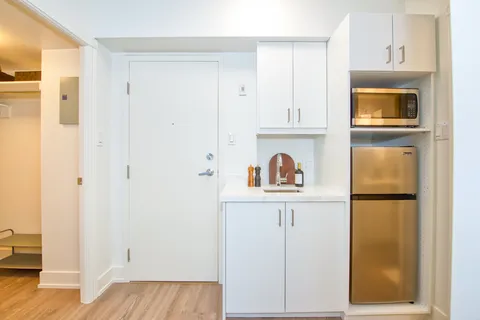 White kitchenette with a sink, refrigerator and microwave.
