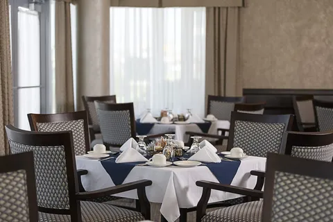 Set dining table with white tablecloths, folded napkins and upholstered wooden chairs