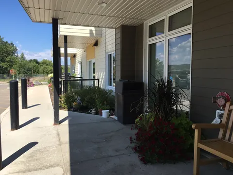 Covered entrance walkway beside windows and planting beds.