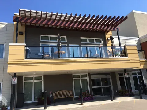 Residence exterior with a balcony and pergola above the entrance.