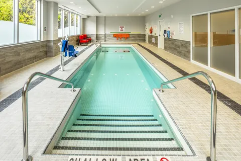Indoor pool with a metal handrail and tall windows