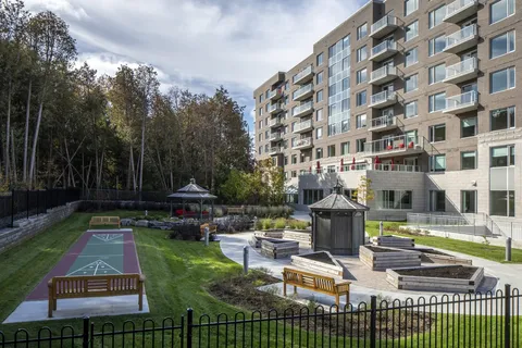 Residence balconies above a garden with gazebos, raised beds and a shuffleboard court