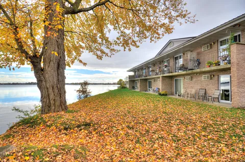 Lakeside side of Birchmere Residence with balconies and autumn leaves on the lawn.