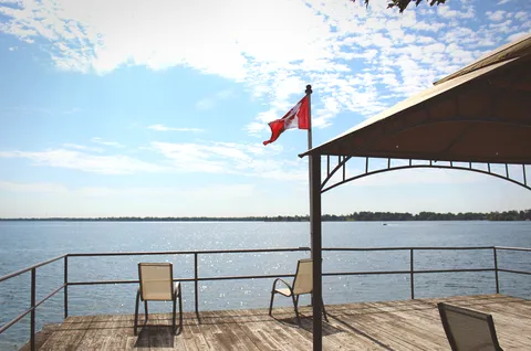 Waterfront terrace with chairs, a railing, a canopy and a Canadian flag.