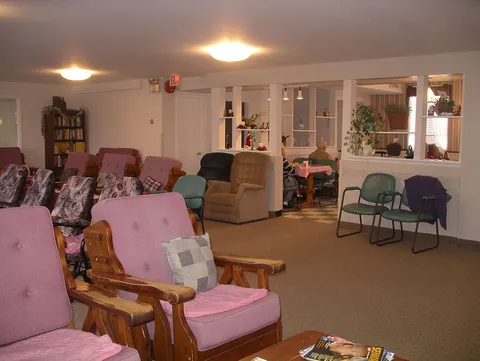 Lounge with upholstered chairs, tables and a fireplace.
