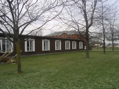 Single-storey brick exterior with a lawn and mature trees.