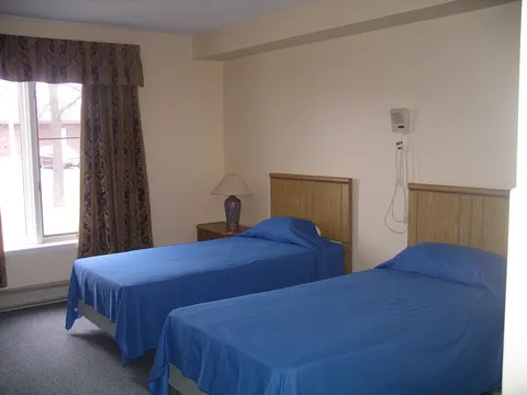 Shared bedroom with two single beds and a curtained window.