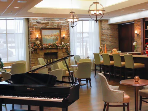 Lounge with a grand piano, armchairs and a stone fireplace.