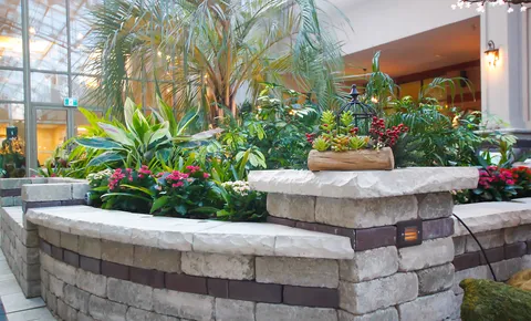 Indoor garden with palms, flowering plants and stone planters.