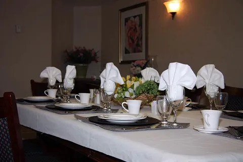 Dining table set with white napkins, dishes, glassware and a floral centrepiece