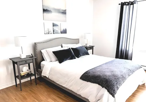 Bedroom with a double bed, bedside lamps, grey curtains and landscape prints