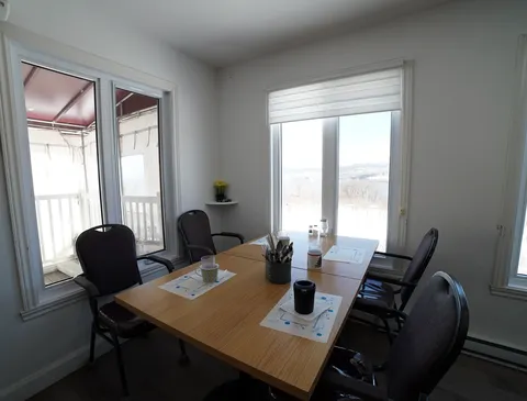 Dining table with four chairs beside windows overlooking a river