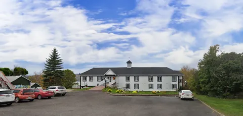 White residence building beyond a driveway and parked cars