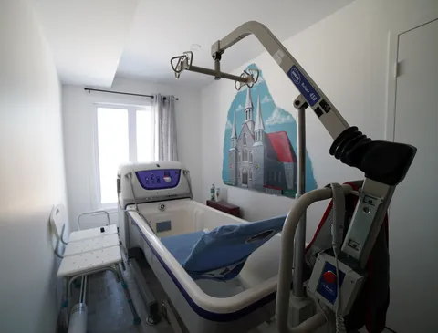 Accessible bathing room with a patient lift and an adjustable bath