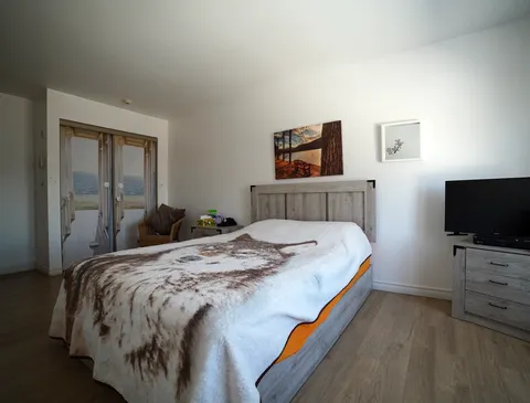 Bedroom with a double bed, bedside furniture, television and framed artwork