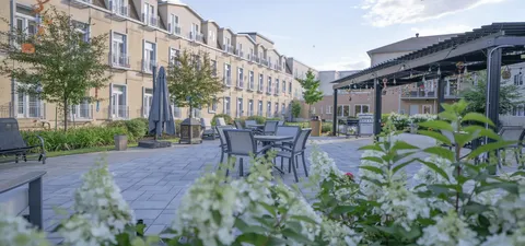Residence buildings around a courtyard with patio tables, chairs and a pergola