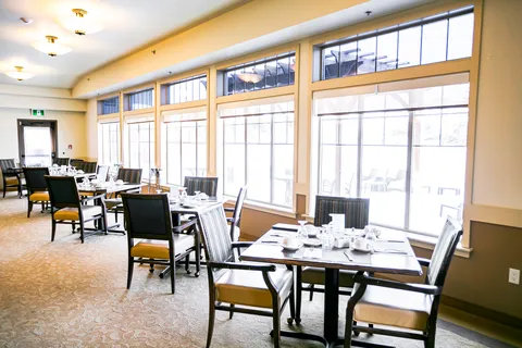 Dining room with set tables beside a row of windows.