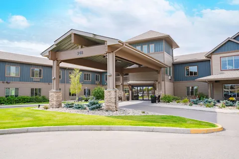 Residence entrance with a covered driveway, stone columns and a lawn.
