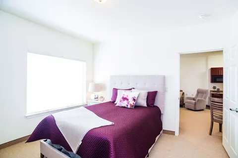 Suite bedroom with a bed, armchair and doorway to the living area.
