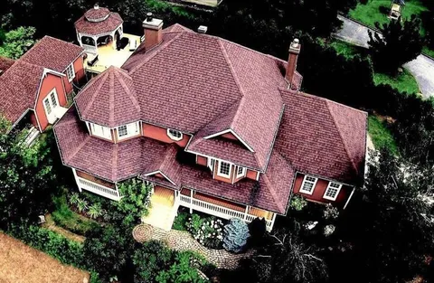 Aerial view of the red residence, roof and surrounding garden.