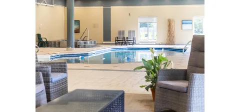 Indoor pool with lounge seating beside a tiled deck