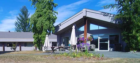 Terrace beside a low building with outdoor tables and umbrellas.