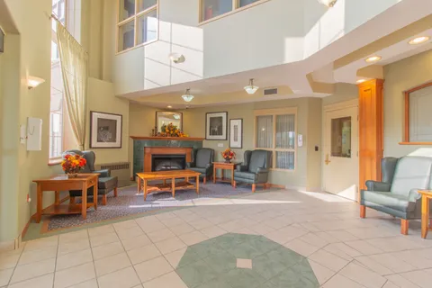Lobby with a stone fireplace, seating and tall windows.