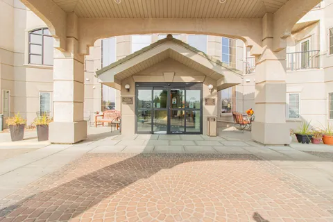 Covered main entrance with glass doors and flower planters.