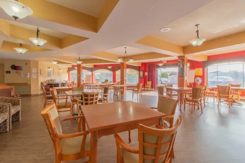 Dining room with wooden tables and chairs beside large windows.