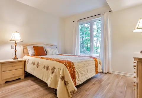 Bedroom with a patterned bedspread, bedside cabinet and patio door