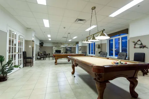 Games room with two billiard tables and large windows.